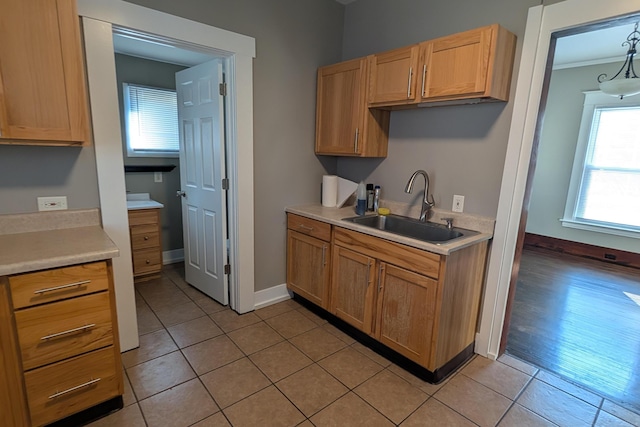 kitchen featuring light countertops, light tile patterned flooring, baseboards, and a sink