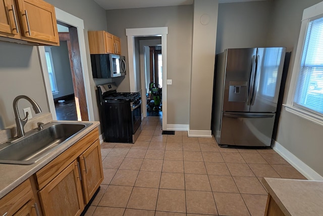 kitchen with light tile patterned floors, stainless steel appliances, baseboards, and a sink