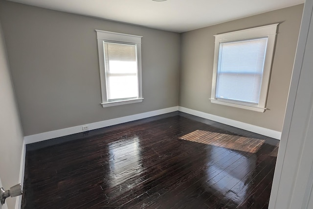 spare room featuring dark wood-style floors and baseboards