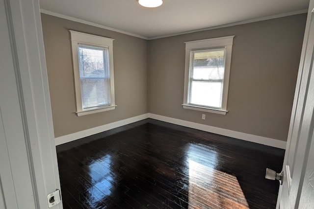 spare room with baseboards, dark wood finished floors, and crown molding