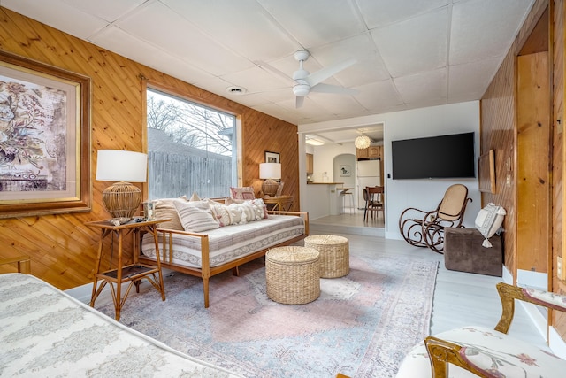 living area with wooden walls and ceiling fan