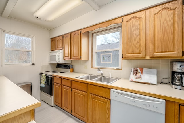 kitchen featuring decorative backsplash, white appliances, light countertops, and a sink