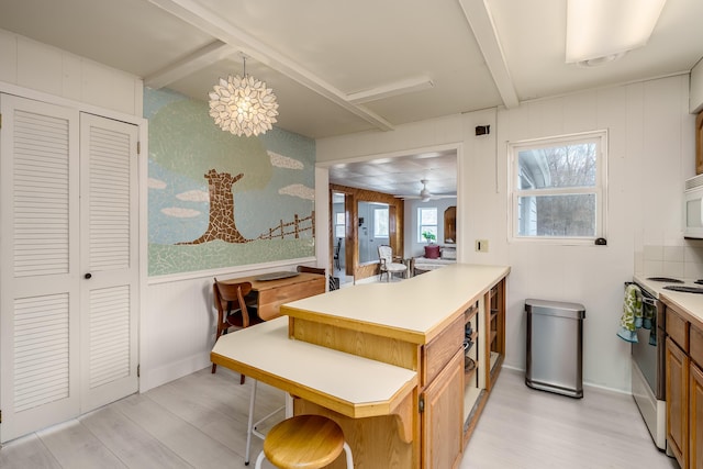 kitchen with white appliances, a peninsula, light wood-style flooring, and light countertops