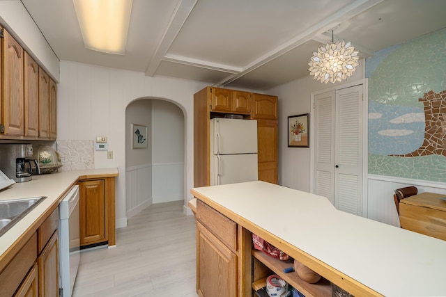 kitchen featuring light wood finished floors, light countertops, beam ceiling, arched walkways, and white appliances