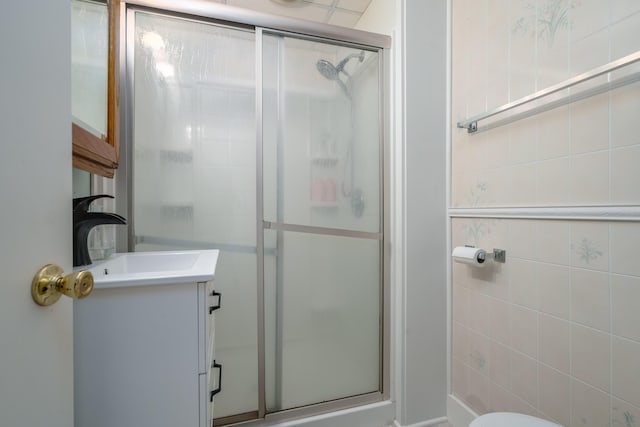 full bathroom with vanity, a shower stall, and tile walls