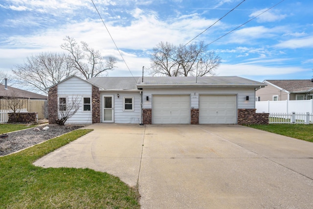 view of front facade with a front lawn, driveway, fence, an attached garage, and brick siding