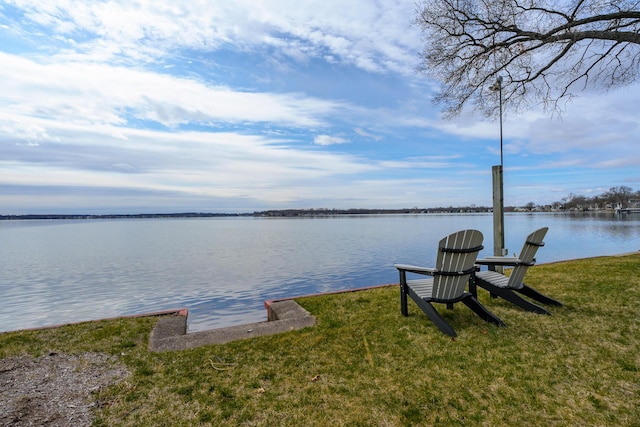 view of dock with a water view and a lawn