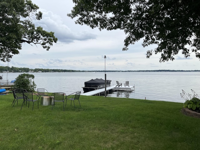 view of dock featuring boat lift, a lawn, and a water view