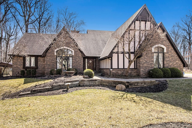 tudor-style house featuring brick siding and a front lawn