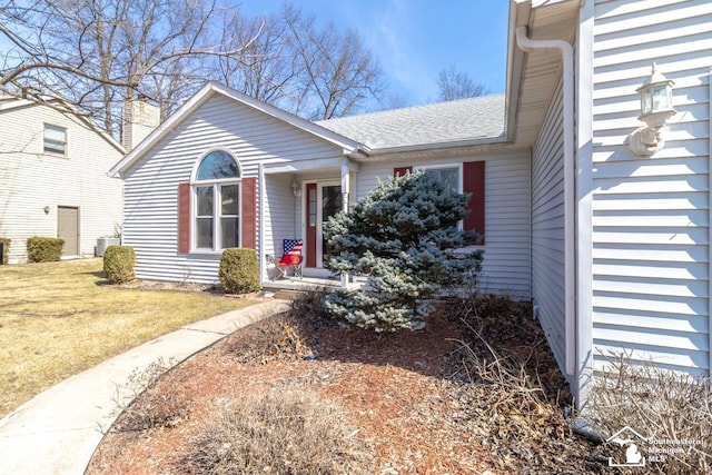 view of front of home with a front yard, a chimney, and a shingled roof