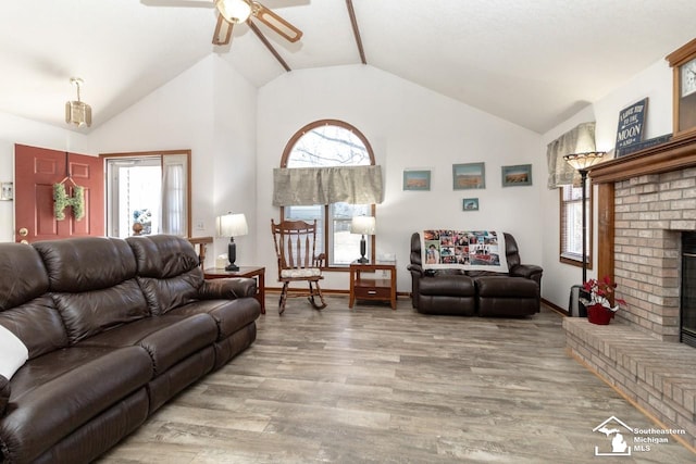 living room with wood finished floors, baseboards, high vaulted ceiling, ceiling fan, and a brick fireplace