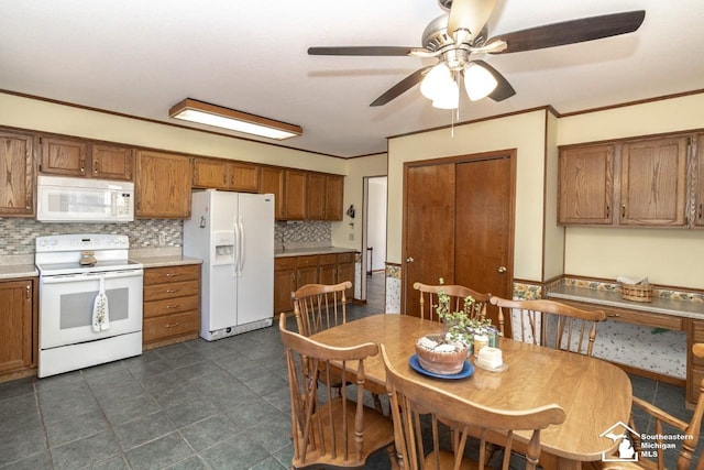 kitchen featuring brown cabinetry, white appliances, crown molding, and ceiling fan