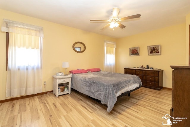 bedroom featuring multiple windows, light wood-style floors, and baseboards