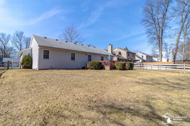 rear view of property featuring a lawn, a wooden deck, and fence