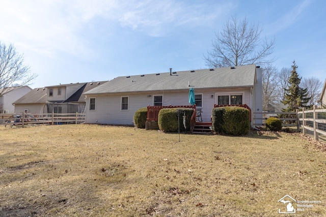 back of house with a fenced backyard, a lawn, and a deck