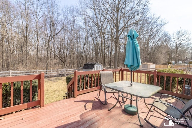 deck with an outbuilding, a shed, and outdoor dining space