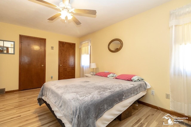 bedroom featuring visible vents, two closets, light wood-style floors, baseboards, and ceiling fan