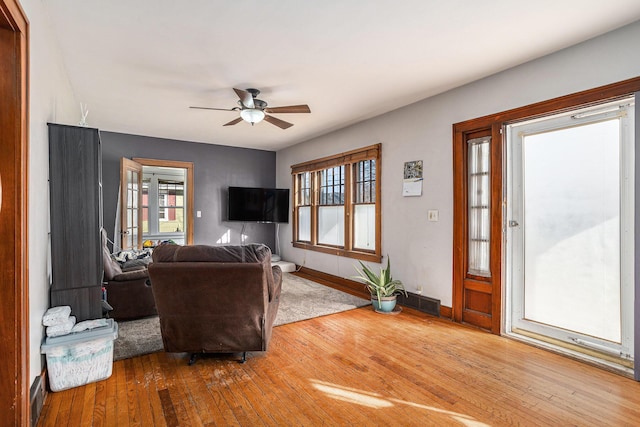 living area with baseboards, wood-type flooring, a healthy amount of sunlight, and ceiling fan