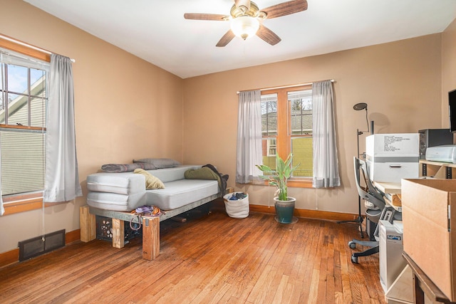 interior space with visible vents, baseboards, ceiling fan, and hardwood / wood-style flooring