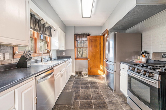 kitchen featuring a sink, stainless steel appliances, dark countertops, and white cabinetry