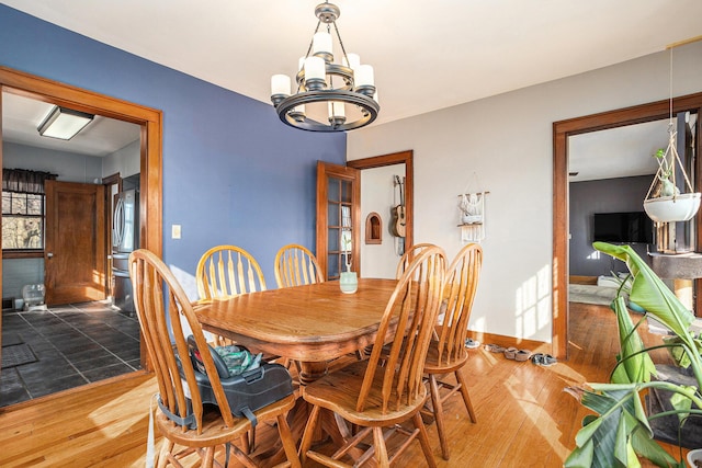 dining space featuring a chandelier, baseboards, and wood finished floors