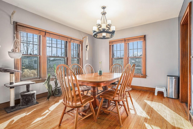 dining room with a chandelier, light wood-style flooring, and baseboards