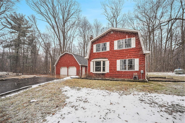 dutch colonial with a gambrel roof, a chimney, and a detached garage