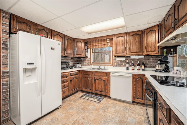 kitchen featuring black appliances, light countertops, under cabinet range hood, and a sink