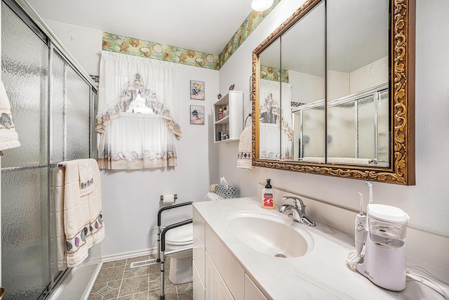 bathroom with baseboards, vanity, a shower stall, and toilet