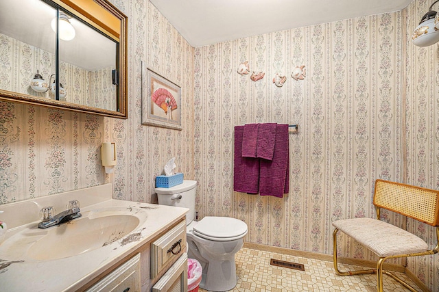 half bathroom featuring visible vents, toilet, wallpapered walls, and vanity