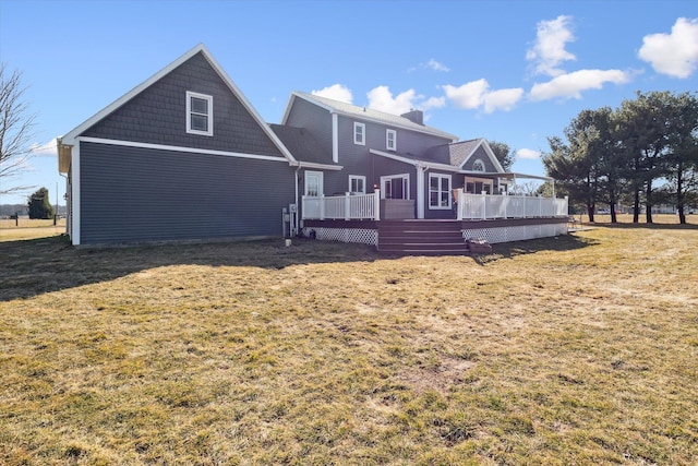 rear view of house featuring a wooden deck, a lawn, and a chimney