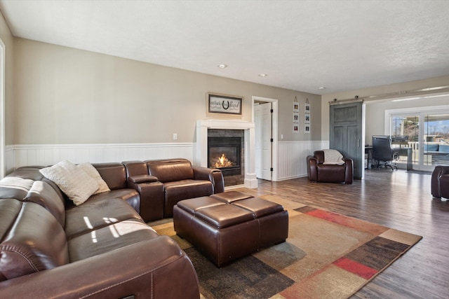 living room featuring a barn door, wood finished floors, a high end fireplace, and wainscoting