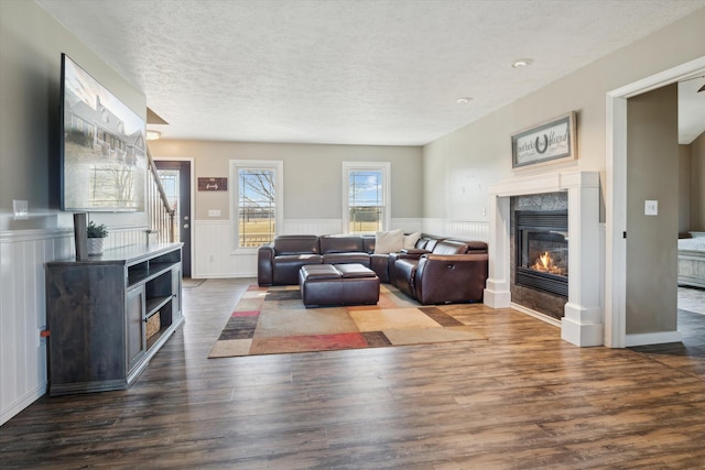 living area featuring a wainscoted wall, a textured ceiling, wood finished floors, and a fireplace