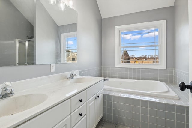 full bathroom with double vanity, a bath, a stall shower, and a sink