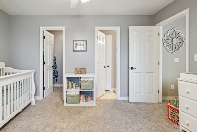 carpeted bedroom with a spacious closet, ceiling fan, and baseboards