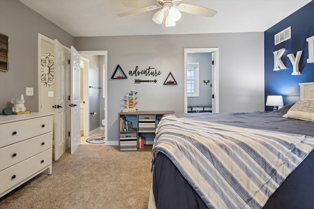 bedroom featuring a ceiling fan, baseboards, visible vents, ensuite bathroom, and light carpet