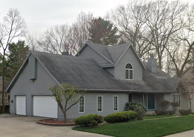 view of front facade featuring concrete driveway, a front lawn, roof with shingles, and a chimney