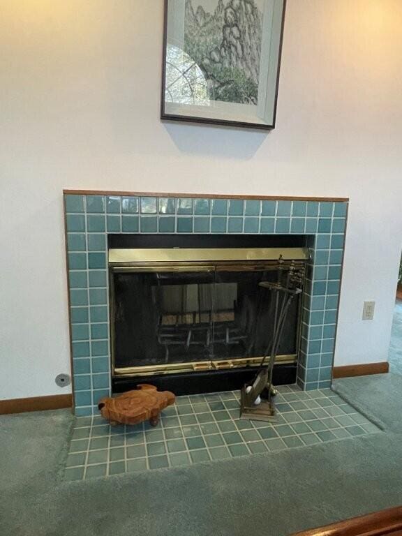 interior details with a tiled fireplace, carpet, and baseboards