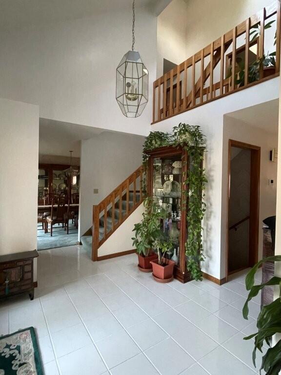 interior space with tile patterned flooring, baseboards, stairs, and a high ceiling