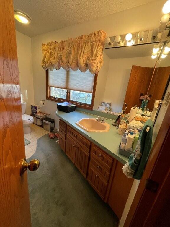 bathroom with tile patterned floors, toilet, vanity, and a textured ceiling