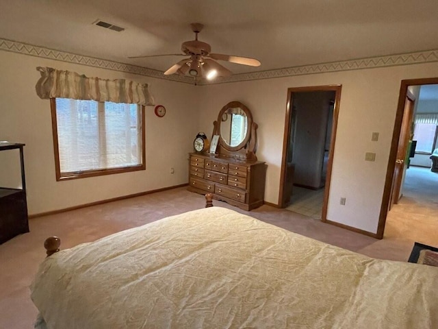 carpeted bedroom with visible vents, baseboards, and a ceiling fan