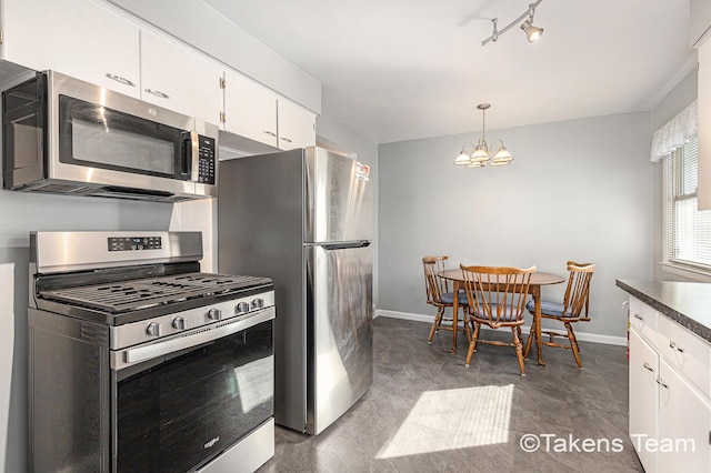 kitchen with a notable chandelier, stainless steel appliances, white cabinets, baseboards, and hanging light fixtures