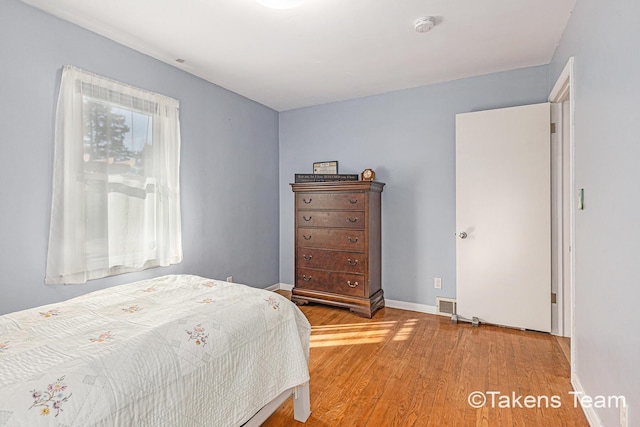 bedroom featuring light wood-type flooring, baseboards, and visible vents