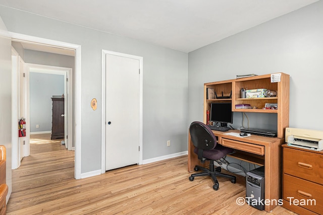 home office with light wood-style flooring and baseboards