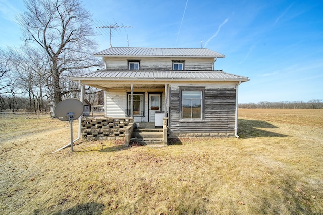 view of front of house featuring covered porch, metal roof, and a front yard