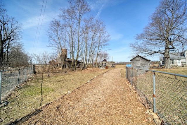 view of yard featuring an outbuilding, driveway, a garage, and fence