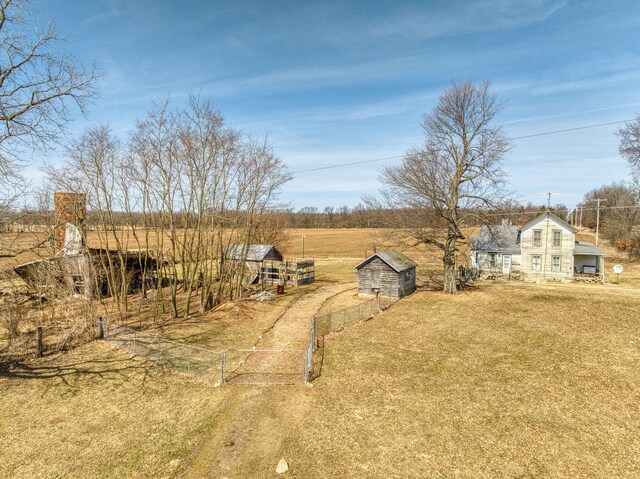 view of yard featuring an outbuilding, fence, driveway, a rural view, and a storage shed