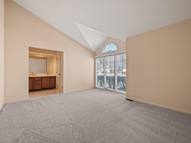 empty room with a sink, visible vents, light carpet, and high vaulted ceiling