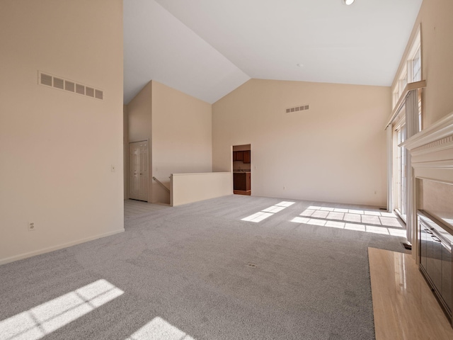 unfurnished living room featuring visible vents, carpet floors, and high vaulted ceiling