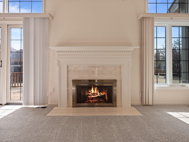 interior details with a fireplace with flush hearth, visible vents, and carpet